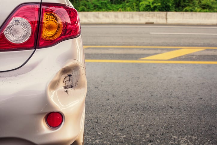 Carolina Collision and Frame Service | Beige car with dented fender parked on the roadside
